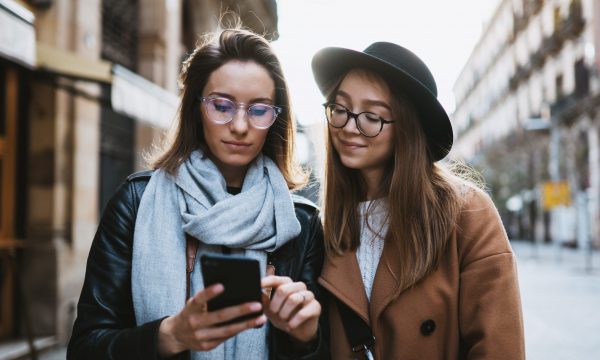 Tourists girls using smartphone plans trip on internet mobile phone. Weekend europe city. Travelers in glasses hold cellphone travels in Barcelona Tourists girls using smartphone plans trip on internet mobile phone. Weekend europe city. Travelers in glasses hold cellphone travels in Barcelona